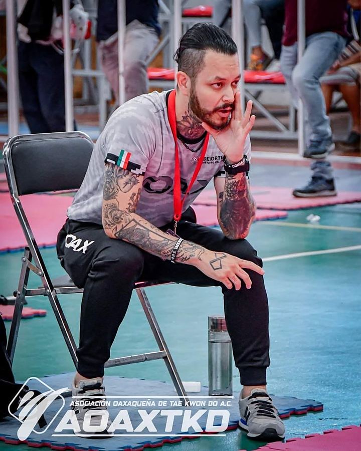 El maestro principal de REAL, sentado en la silla de coach, sigue con atención un combate de torneo