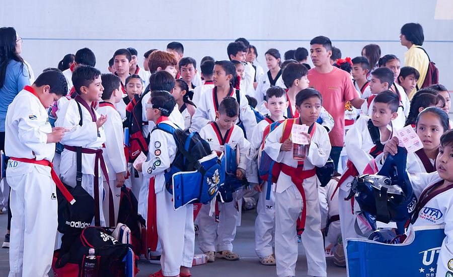 Muchos niños con dobok y protecciones esperan su turno en un torneo