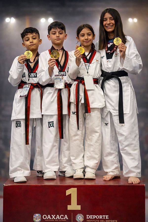 Tres niños y una joven del equipo muestran sus medallas de oro en el primer lugar del podio
