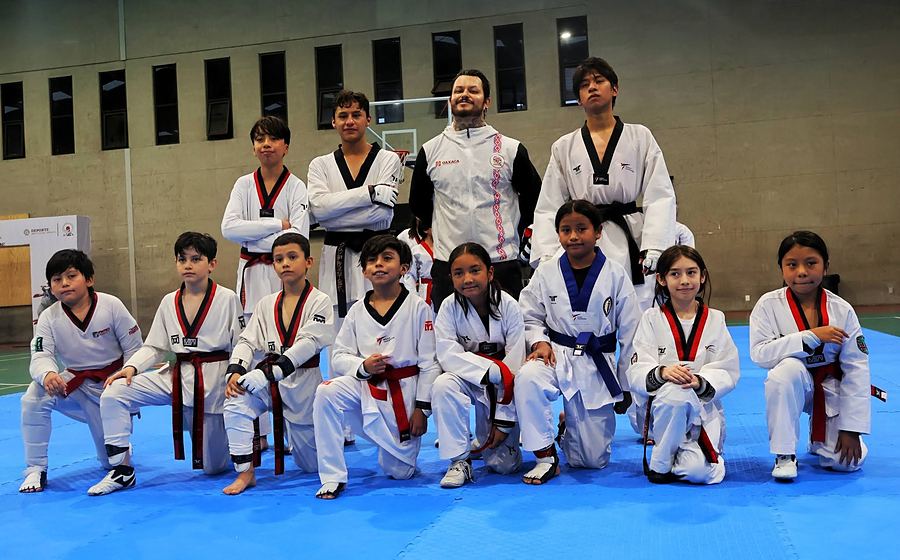 Niñas, niños y jóvenes del equipo REAL con dobok posan con su maestro sobre el tatami